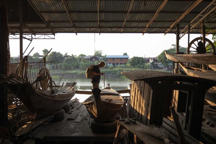 François Pécheux regarde une embarcation ancienne, en arrière plan on aperçoit le fleuve
